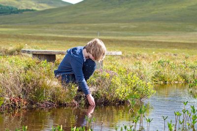 Girl crouching by stream