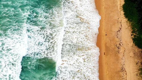 High angle view of sea waves splashing on beach