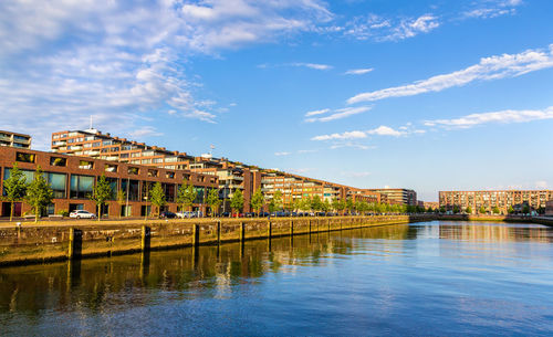Bridge over river by buildings against sky in city