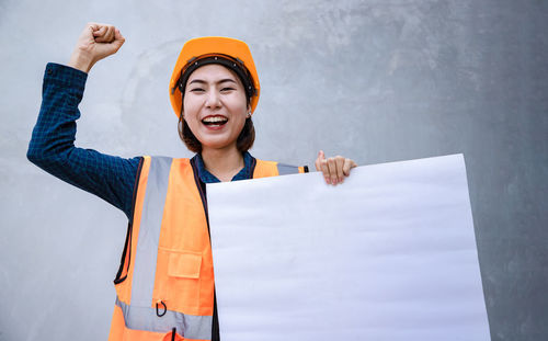 Smiling young woman standing against orange wall