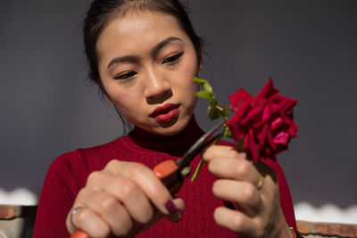 Portrait of woman holding red flower