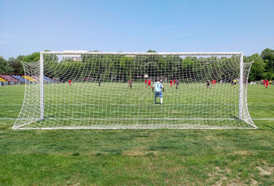 People playing soccer on field against sky