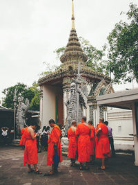 Rear view of people walking by building against sky