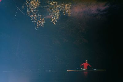 Man in sea against sky at night