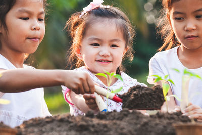 Happy girls gardening while planting saplings