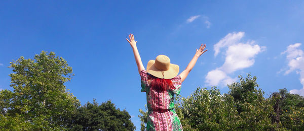 Rear view of woman standing against blue sky