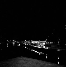 Illuminated city by river against clear sky at night