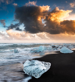 Beautiful ice chunks on black sand beach at diamond beach during sunset