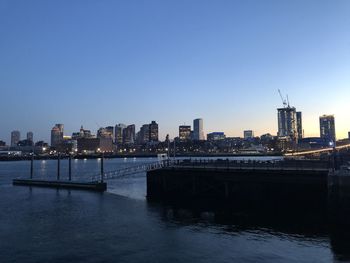 Scenic view of river by buildings against clear sky