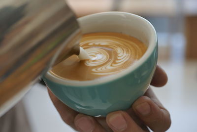 Close-up of hand holding coffee cup