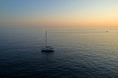 Boats sailing in sea at sunset