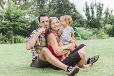 Portrait of parents with daughter sitting on field in park
