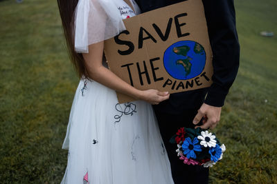 Beautiful newlyweds are kissing while holding a sign that says save the world