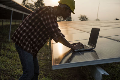 Rear view of man using laptop on table