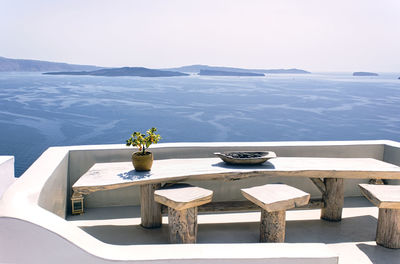 Chairs and table by sea against sky