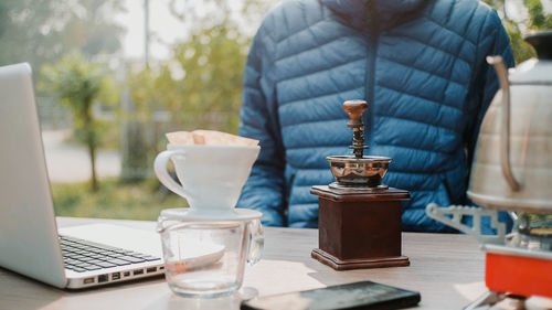 Close up manual coffee grinder for grinding coffee beans on wooden desk in morning.