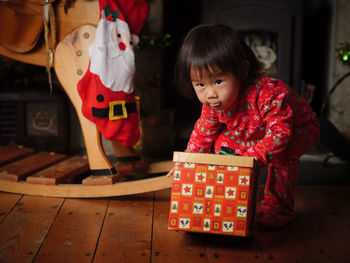 Girl with gift box by toy at home