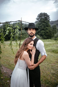 Man embracing beautiful woman while standing on grassy field