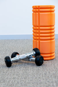 Close-up of foam roller and dumbbells on floor