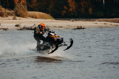 Sportsman on a snowmobile rides on the water