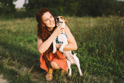 Beautiful woman plays with her jack russell dog in the park.