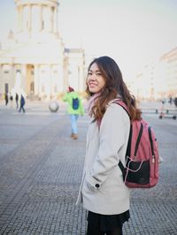 Young woman standing on sidewalk in city