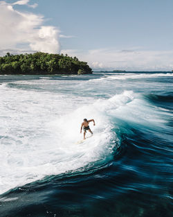 Man surfing in sea against sky