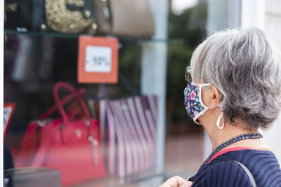 Close-up of woman wearing mask looking at bags in store