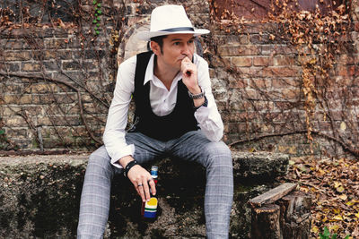 Full length of young man sitting outdoors