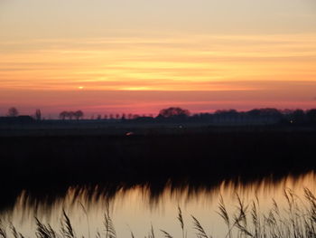 Scenic view of silhouette field against romantic sky at sunset