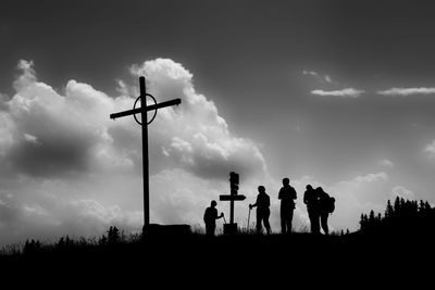 Silhouette people standing on field against sky during sunset