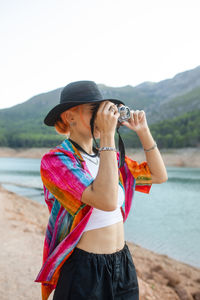 Woman with black hat in a lake taking pictures of the landscape