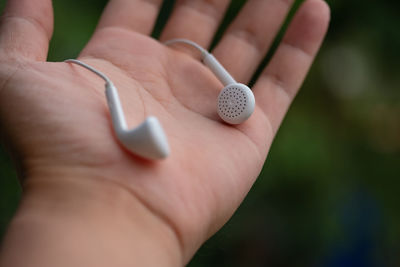 Close-up of hand holding in-ear headphones