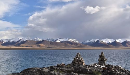 Scenic view of lake by snowcapped mountains against sky