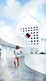 Woman standing in colonnade against building