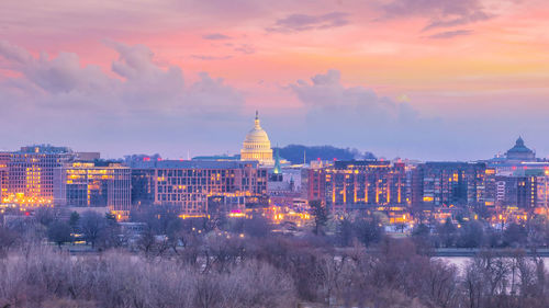 Illuminated buildings against sky during sunset