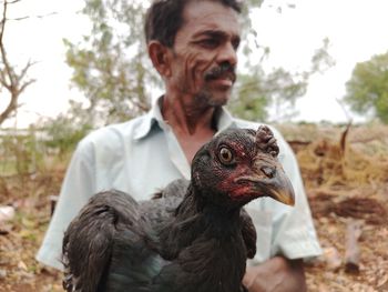 Man holding hen outdoors