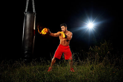 Full length of shirtless man standing against black background