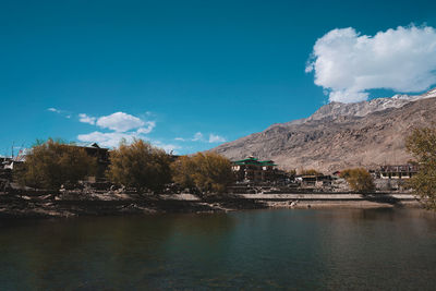 Scenic view of river by buildings against blue sky