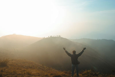 Rear view of man standing on mountain against sky