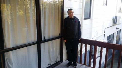 Portrait of young man standing against window