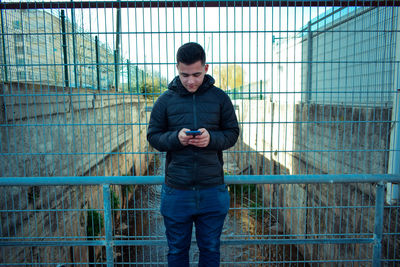 Full length of young man standing against fence