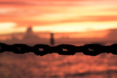 Close-up of silhouette chain against sky during sunset