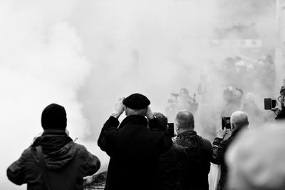 People photographing while standing amidst smoke