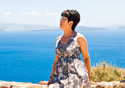 Young woman looking at sea against sky