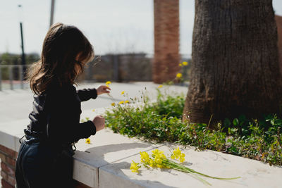 Woman standing by flower tree trunk