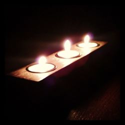 Close-up of lit candle in dark room