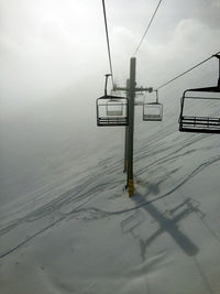 Ski lift on snowcapped mountain against sky