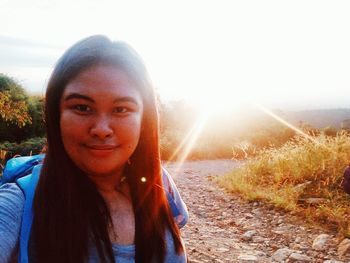 Portrait of smiling young woman against sun