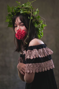 Portrait of beautiful woman holding flower standing against blurred background